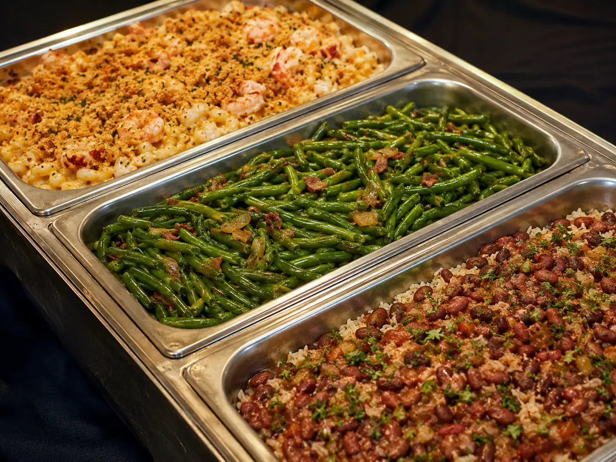 Catering pans with seafood macaroni, green beans, and red beans with rice